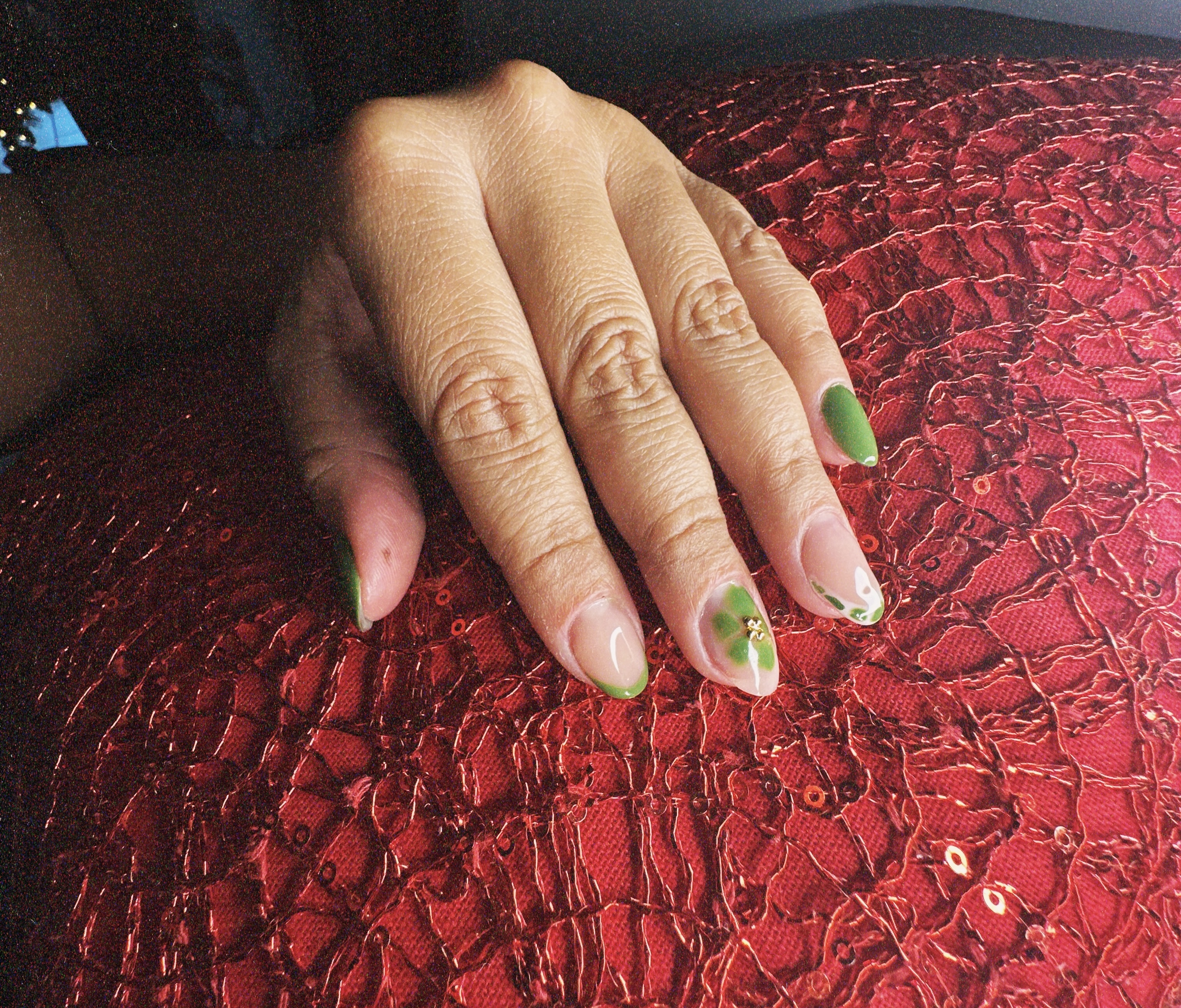 Acrylic nail manicure with floral nail art and gold details.
